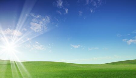 A green field with blue sky and cloudsの写真素材