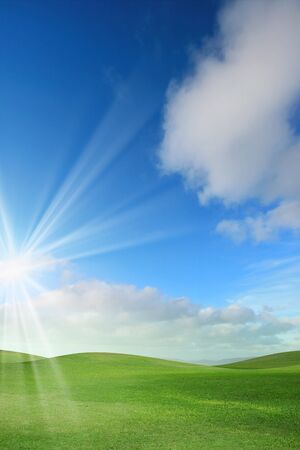 A green field with blue sky and cloudsの写真素材