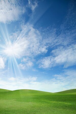 A green field with blue sky and cloudsの写真素材
