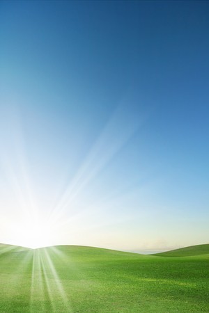 A green field with blue sky and cloudsの写真素材