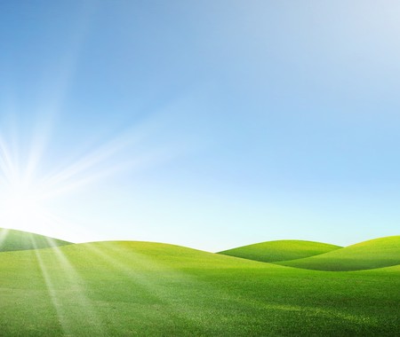 A green field with blue sky and cloudsの写真素材