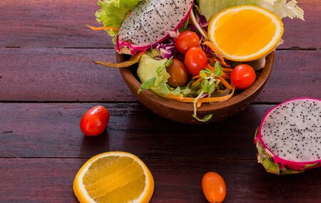 fresh fruits salad in wood bowl on the wood tableの写真素材