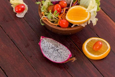 fresh fruits salad in wood bowl on the wood tableの写真素材