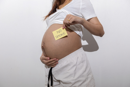 Teenager girl be pregnant in education age in white suit on isolated backgroundの写真素材
