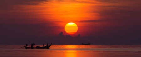 Beautiful sunrise with a fishing boatの写真素材