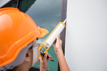 Construction workers installing windows and using siliconの写真素材