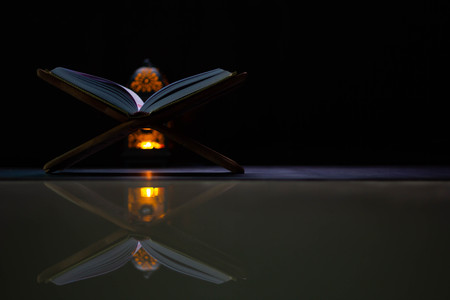 Quran - holy book of Muslims around the world, placed on a wooden board, black background
