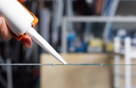 Men's hand uses silicone adhesive with adhesive to connect the mirror with aluminum.の写真素材