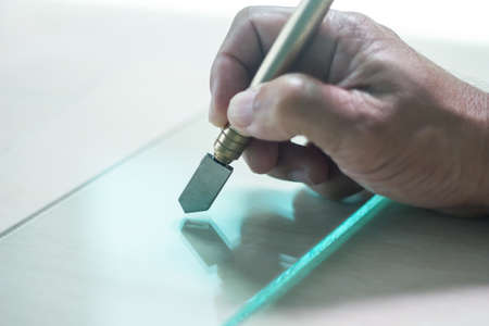 Glass technicians are cutting glass using glass tools according to the customer's order.