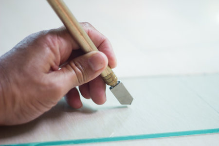 Glass technicians are cutting glass using glass tools according to the customer's order.