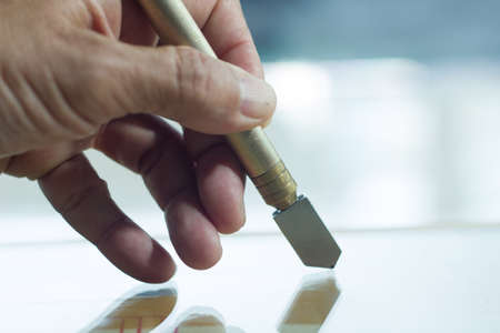 Glass technicians are cutting glass using glass tools according to the customer's order.の写真素材