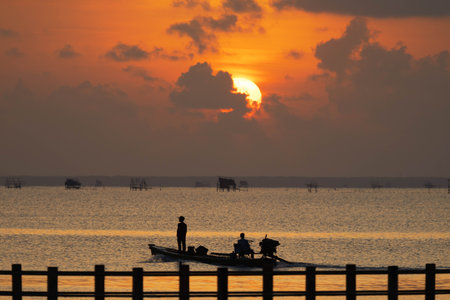 Silhouette of fishermen on the boat at sunset, Thailand.の写真素材