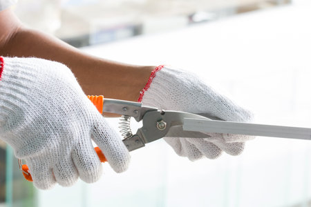 Close up of hand of worker cutting metal with pruning shears