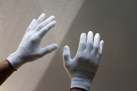 hand in white gloves on the background of the wall, close-upの写真素材