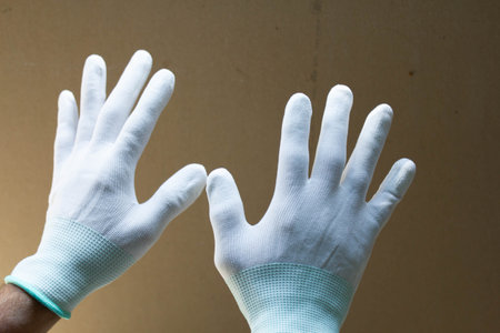 Hand in white rubber gloves on a brown background. Close up.