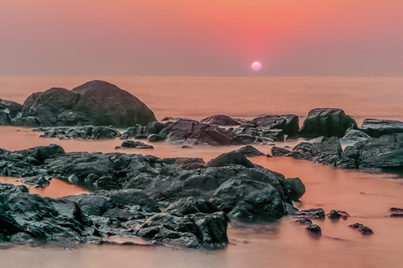 Pink sunset, pink sea, gray stones. Evening landscape.の写真素材