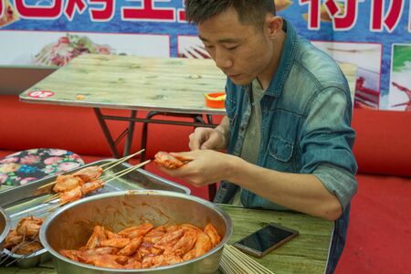 Suifenhe, China 06.16.2017: Street food in China, a shish kebab from chicken wings, a Chinese makes a shish kebab in the streetのeditorial素材