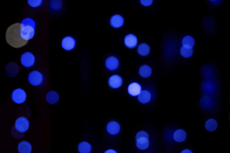 Blue blurred circles on a black, dark background. Festive background, bokeh.の写真素材