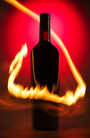 Bottle of wine on the red background with flamesの写真素材