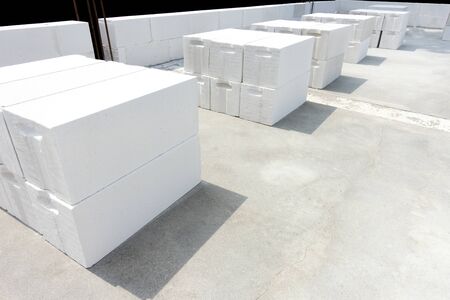 White foamed lightweight concrete (aerated concrete block) laying in stacks on the concrete floor inside under construction industrial building. Background with negative space (copy space).の写真素材
