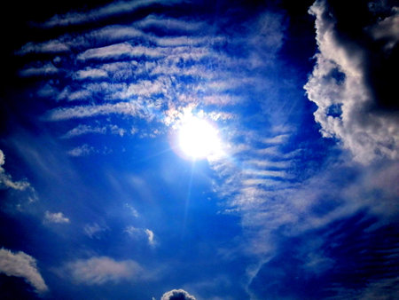 Sun in blue sky with white clouds and sunbeams. Background
