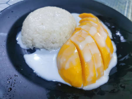 Sticky rice with mango and sticky rice in black plate on tableの写真素材