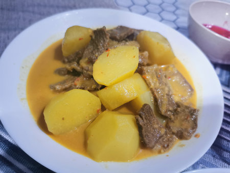 Stewed beef with potatoes in a white plate on a blue backgroundの写真素材