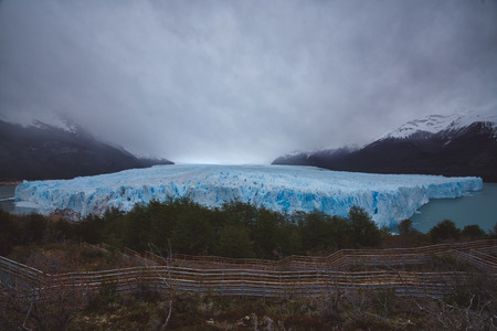Panoramic view of picturesque landscape with blue ice of big melting glacier, green trees and...