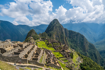 Picturesque view of famous ruins of ancient Inca city of Machu Picchu in Peru, with vivid green grass and steep Huayna Picchu mountain in backgroundの写真素材