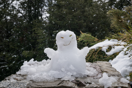 Snowman made of fresh white snow on a rock in mountain woodland conceptual of Christmas holiday seasonの写真素材