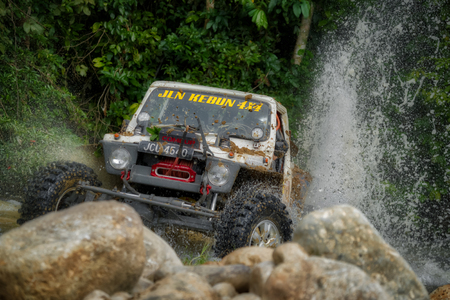 KELANTAN, MALAYSIA - NOVEMBER 2018 : 4x4 vehicle driving in the Rainforest Challenge in Kelantan, Malaysia crossing through a spray of water onto large boulders and rocksのeditorial素材