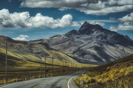 Tarred valley through the Peruvian highlands with tall mountain peaks and deep valley