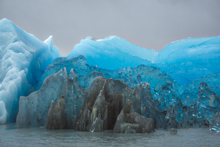 Vivid blue color of melting ice of a glacier in Patagonia, viewed in closeup against cloudy skyの写真素材