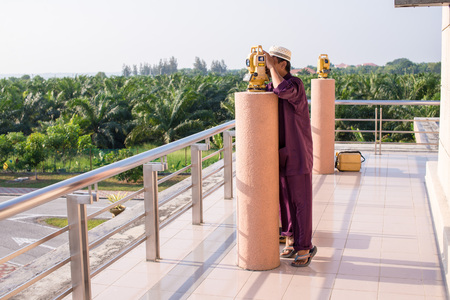 A man looking through a measuring instrument to adjust the tracking of the sun position during sunset to determine new moon phase.の写真素材