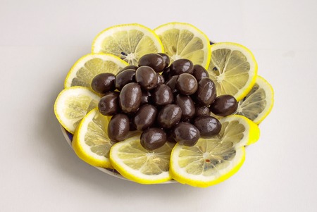 Food. Vegetarian. Black olives and segments of a lemon in a plateの写真素材
