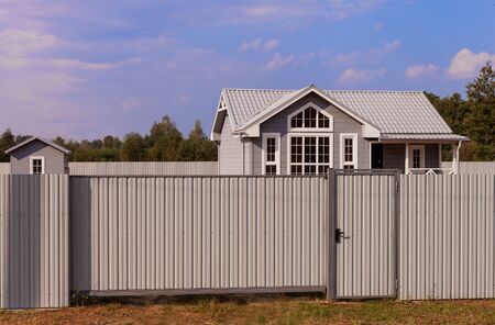 Russia. The country one-storey house with big windows behind a gray fenceの写真素材