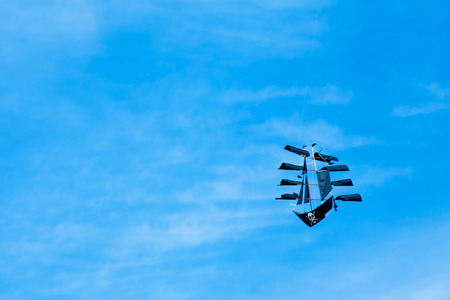 Kite like ship with jolly roger flying on the blue sky in the kite festivalの写真素材