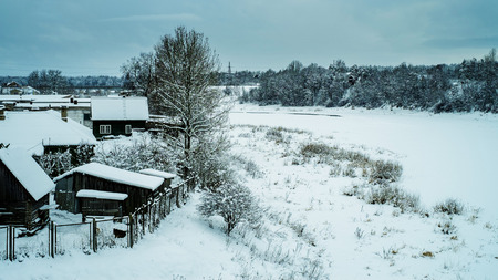 Snowy village on the bank of the river in winterの写真素材