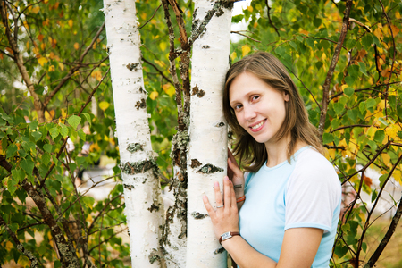 Young pretty woman near birches in parkの写真素材