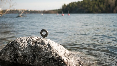 Metal ring for boat rope fasten inside a rock by the lake shore.