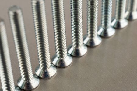 An even number of metal screws standing on a metal sheetの写真素材