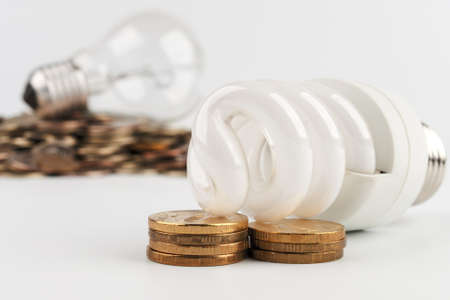 Energy saving lamp on the background bulb lying on gold coinsの写真素材