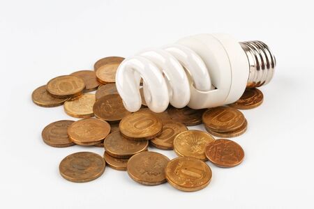 Energy saving light bulb lying on coins. On a white background.の写真素材