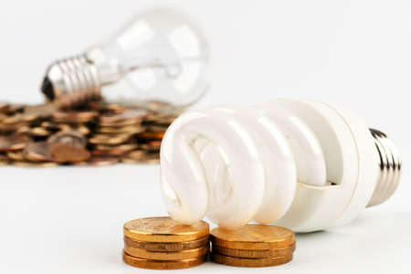 Energy-saving lamp and incandescent lamp lying on gold coinsの写真素材