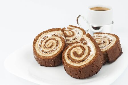 Four chocolate roll on a plate with a cup of coffeeの写真素材
