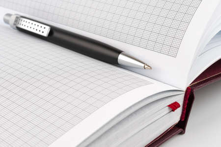 Black ballpoint pen lying in between the pages of a notebookの写真素材