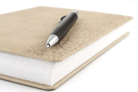 Black ballpoint pen on diary beige on a white backgroundの写真素材