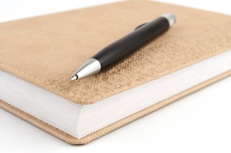 Black ballpoint pen on diary beigeの写真素材
