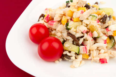 Crab salad and two tomatoes on the corner of a white plateの写真素材