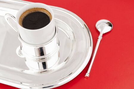 A cup of coffee on a metal tray with a red backgroundの写真素材